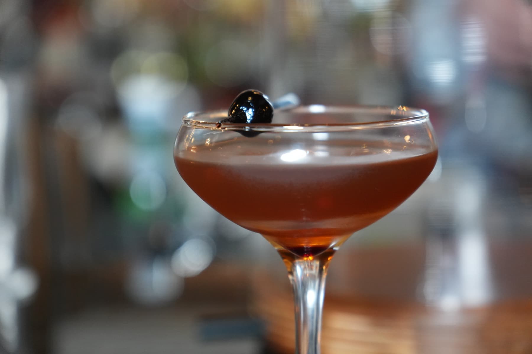 Amber stirred cocktail in a coupe, finished with a brandied cherry